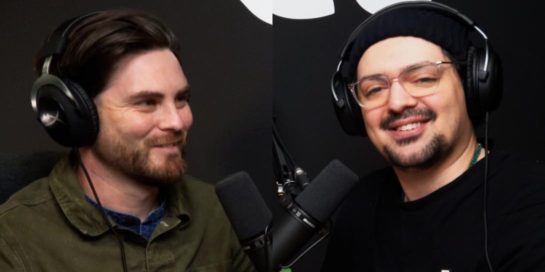 Image shows Tom our head of Development and our content manager Matthew posing in front of the camera. They are both smiling wearing black Tshirts. Matthew Barter is wearing glasses and a black beanie hat. Tom is not wearing any glasses or a hat, but black headphones on his head. 