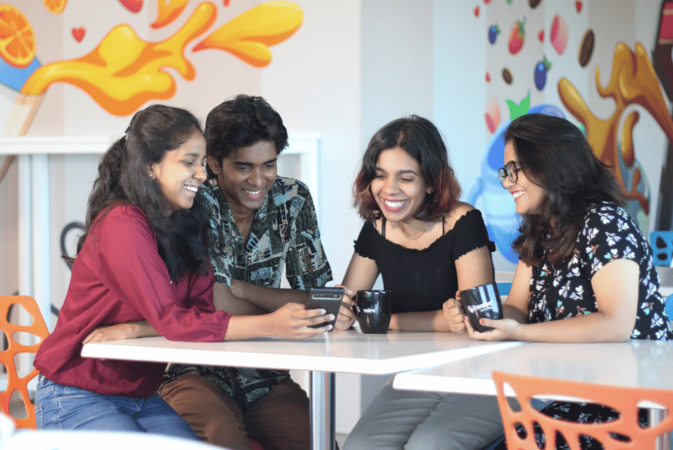 A group of people playing together a mobile game by the table