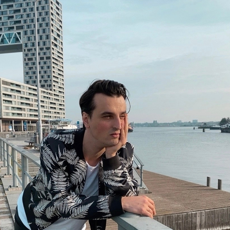 Alex Severino, our colleague, gazes out over a tranquil river with a steel bridge stretching into the distance. The calm waters reflect the serenity of the moment, while the bridge stands as a symbol of connection and journey ahead.